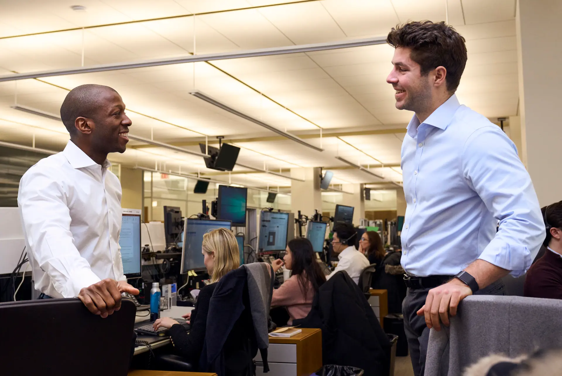 Colleagues in conversation at their desks